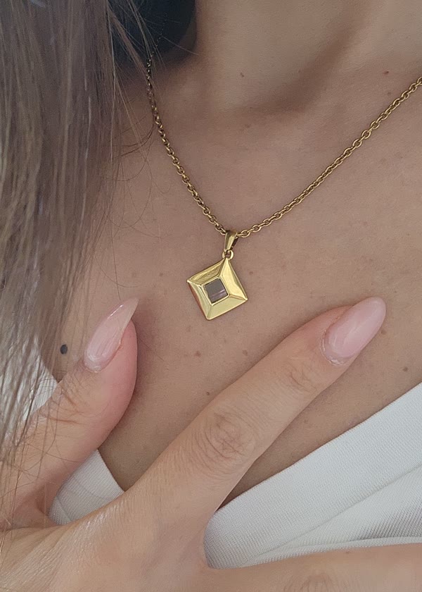 The diamond piece, gold tone, on a chain, close up