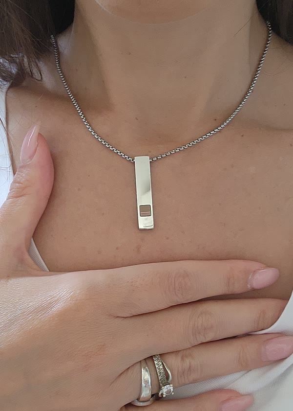 The tall piece, silver tone, on a chain, close up